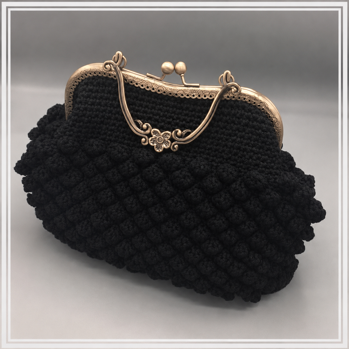 A black crocheted clutch purse with a textured bobble pattern, featuring a gold-tone metal kiss-lock frame and handle.

