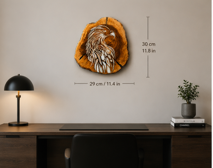 A decorative wood slice wall art piece featuring a carved eagle design, shown mounted on a beige wall above a desk. Black dimension lines and text indicate the piece is 29 cm by 30 cm (11.

